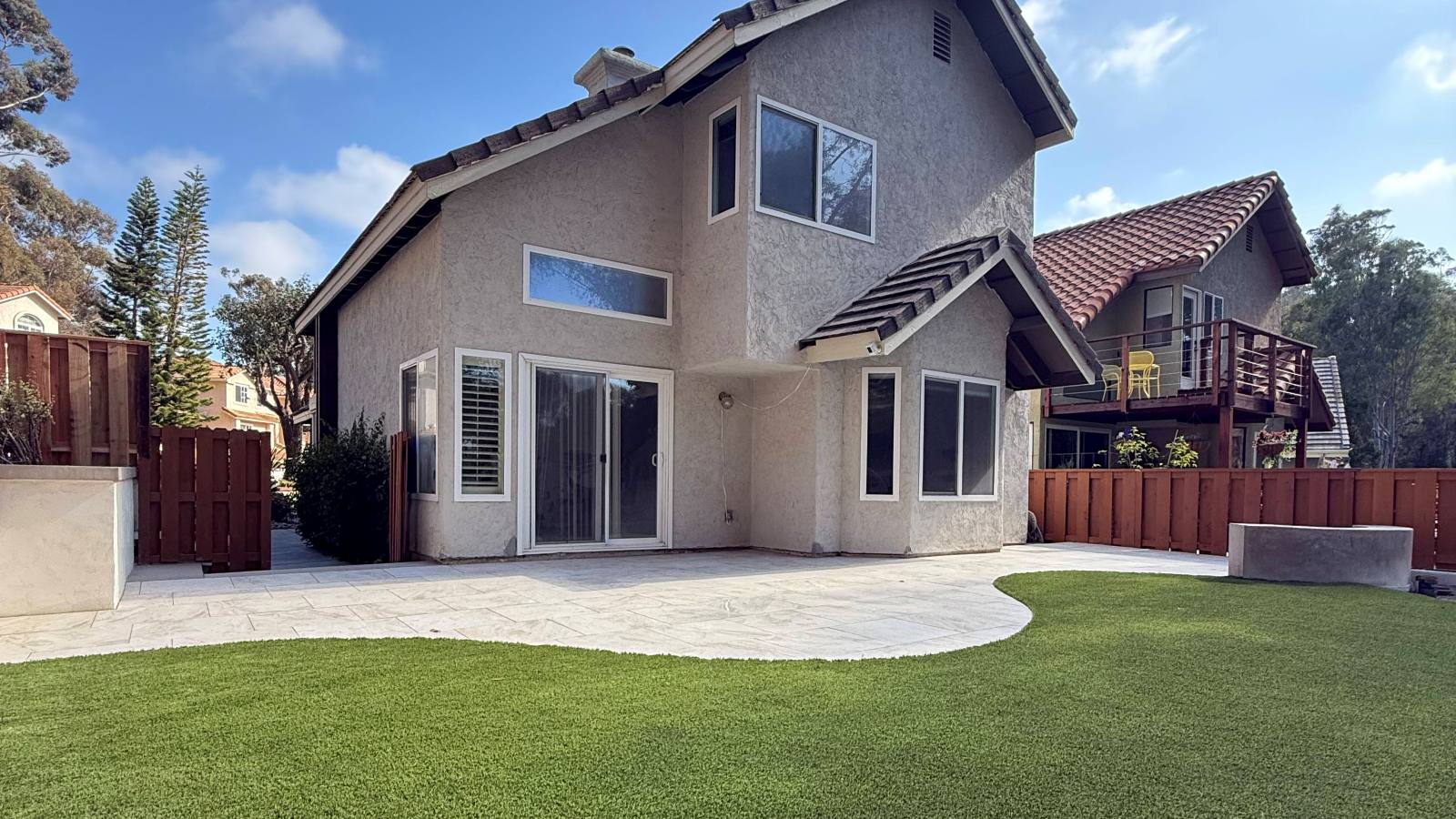 Finished backyard with a curved concrete patio and artificial turf, Carlsbad