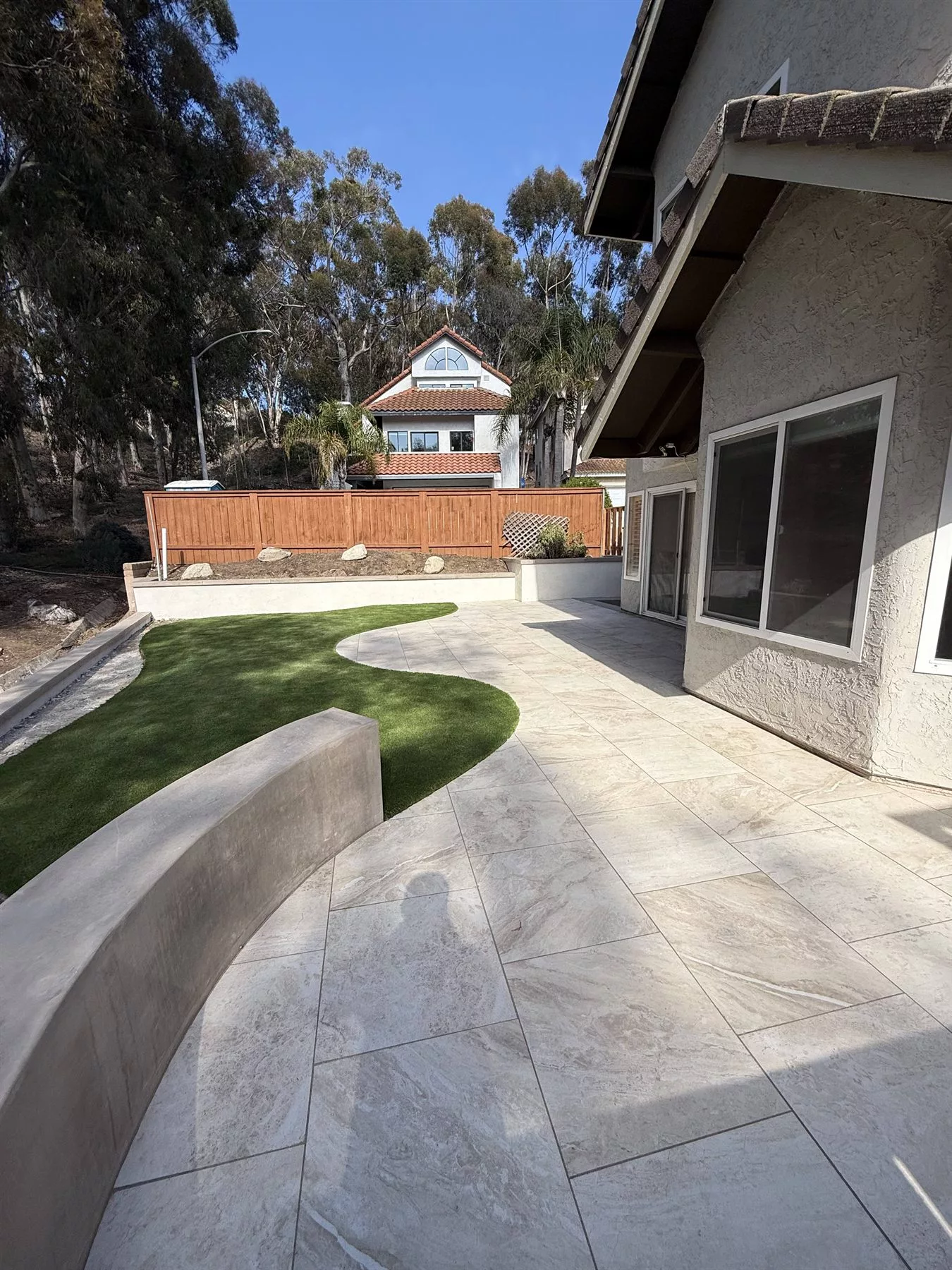Curved premium artificial turf meeting large-format porcelain pavers in a completed Carlsbad backyard