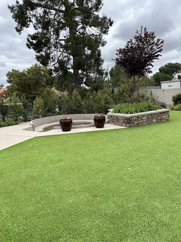 Custom concrete seating area with artificial turf and stone veneer planter in Ramona, CA